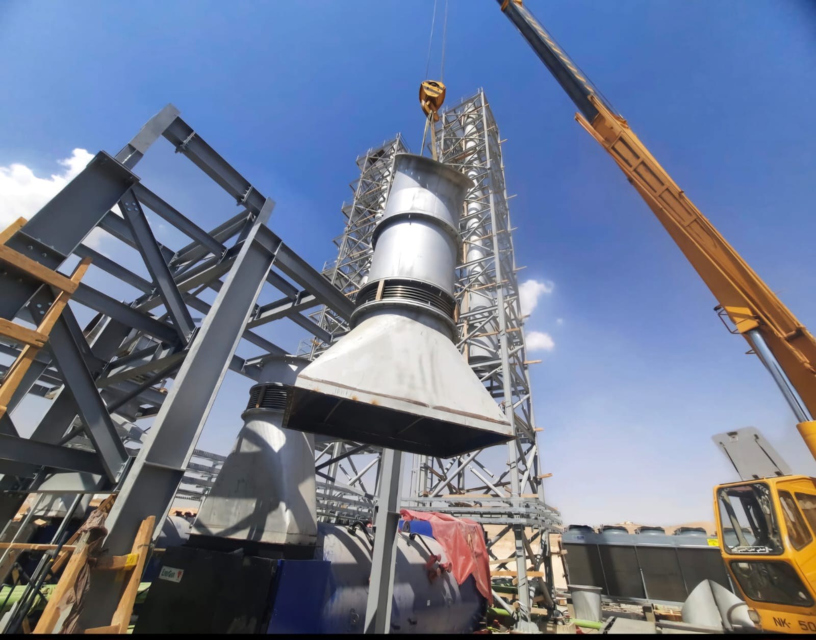 E&M crew lifting a large industrial vessel into a steel structure with a mobile crane